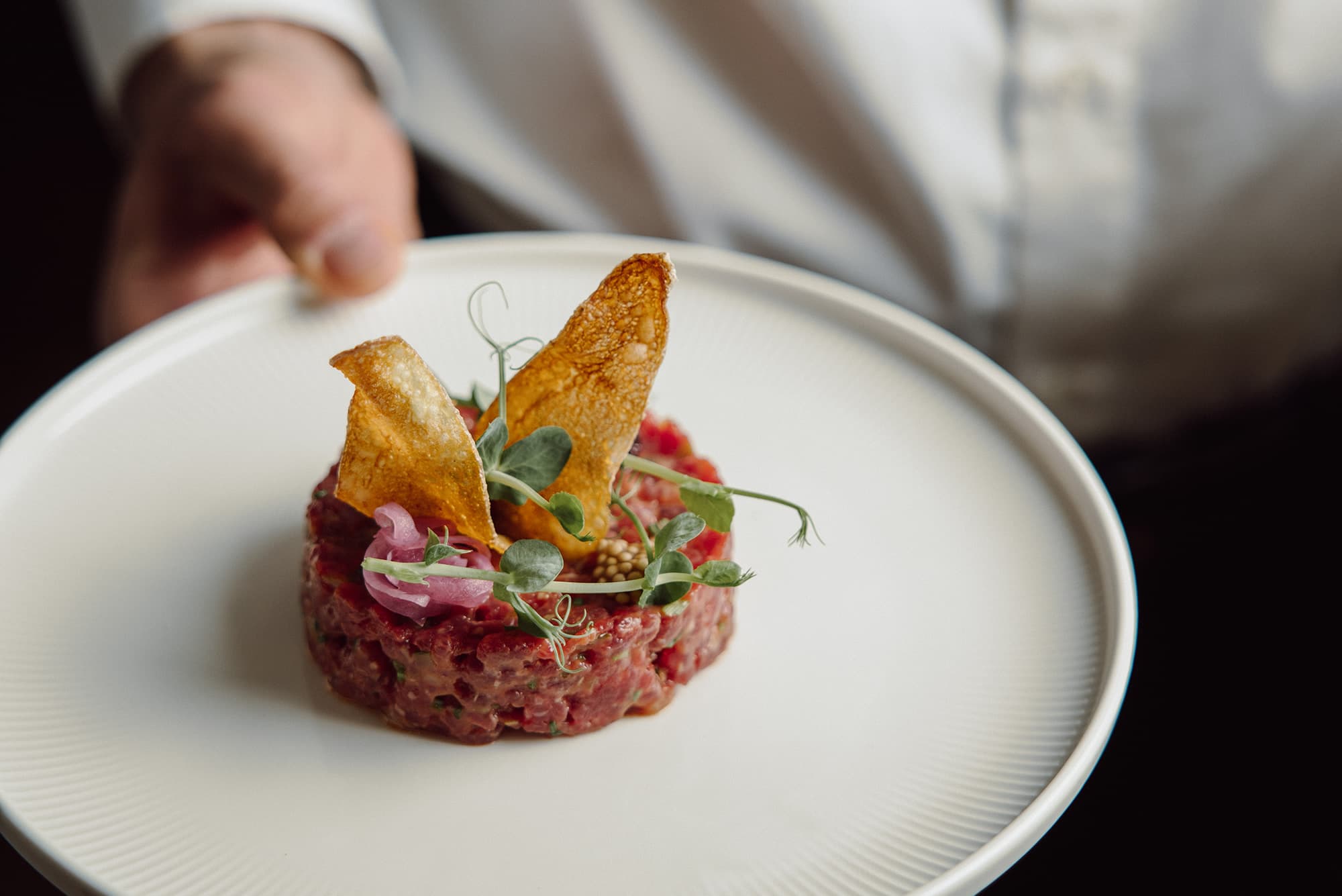 Signature dish Beef Tatar, garniert mit Chips und Kräutern vom Küchenchef Joseph Oberreiter